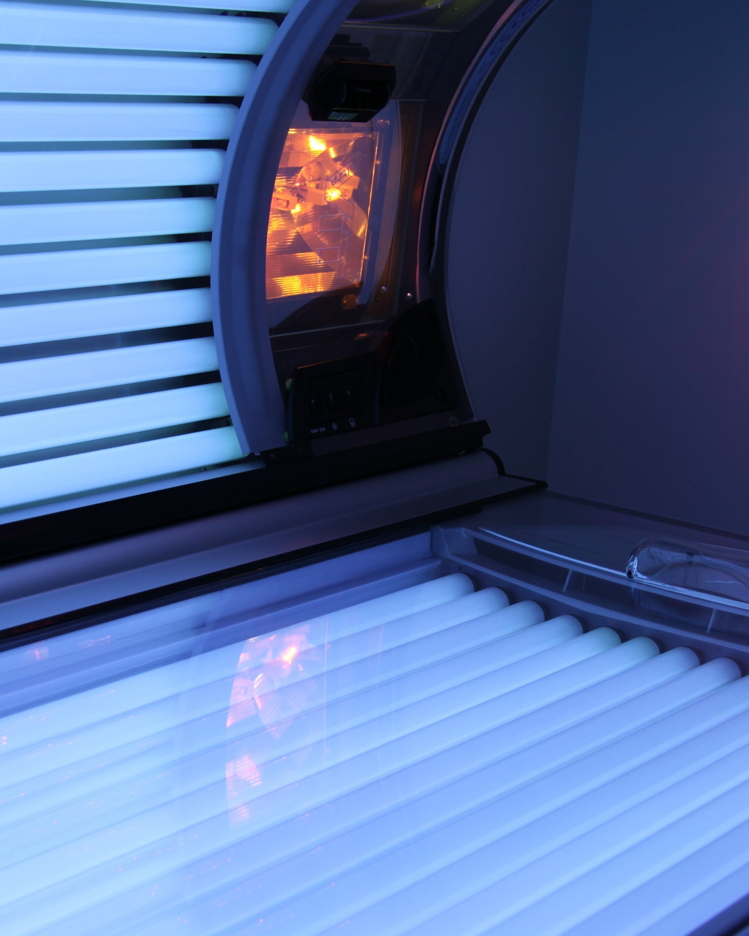 Tanning bed with glowing interior and closed window blinds