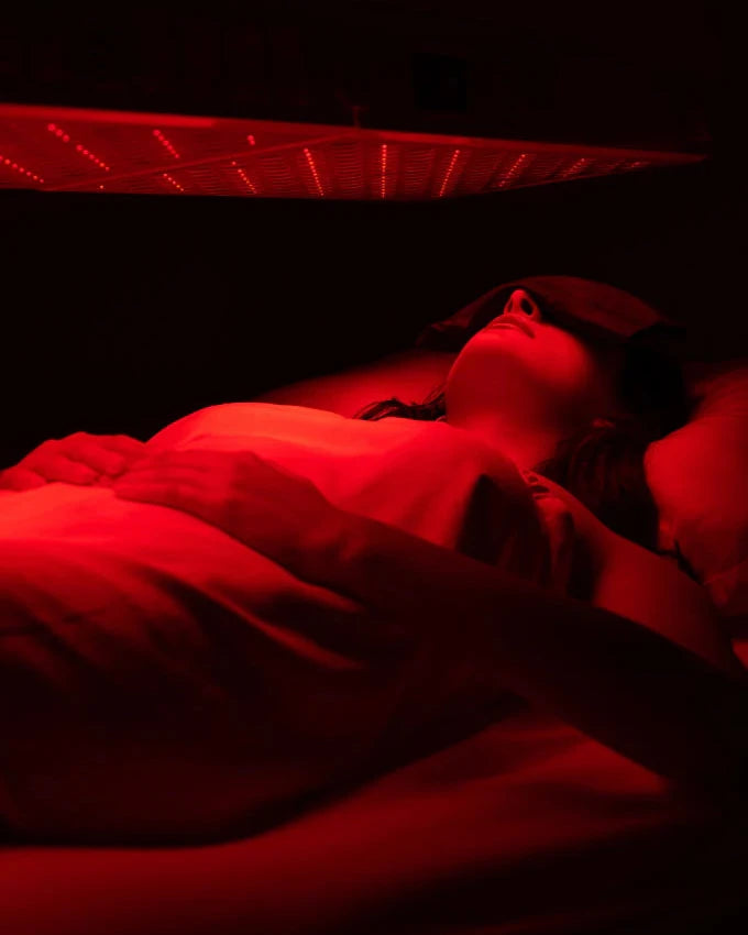Person lying down in a red light therapy chamber.