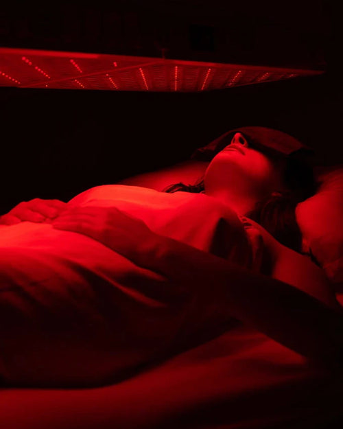 Person lying down in a red light therapy chamber.